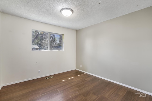unfurnished room with visible vents, baseboards, a textured ceiling, and wood finished floors