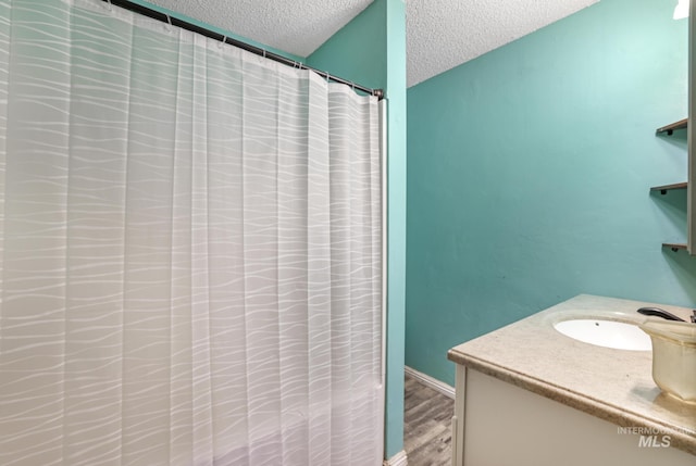full bath with a shower with shower curtain, vanity, a textured ceiling, and wood finished floors