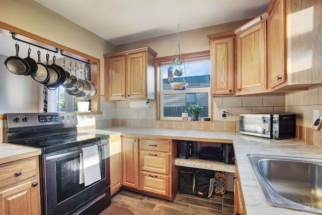 kitchen with stainless steel electric range oven, a sink, light countertops, dark wood finished floors, and tasteful backsplash