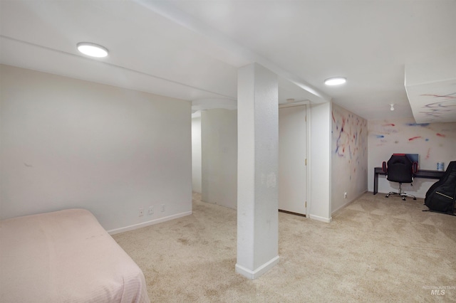 finished basement with carpet floors, a desk, and baseboards