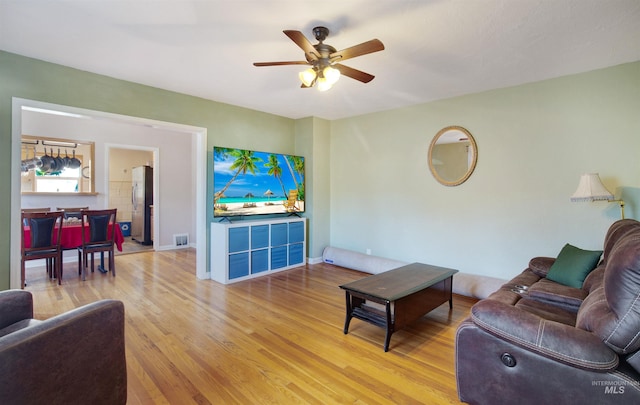 living area with wood finished floors, a ceiling fan, and baseboards