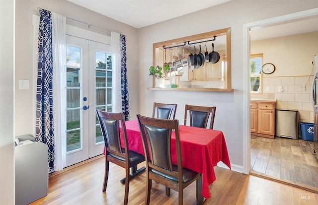 dining area with light wood finished floors and french doors