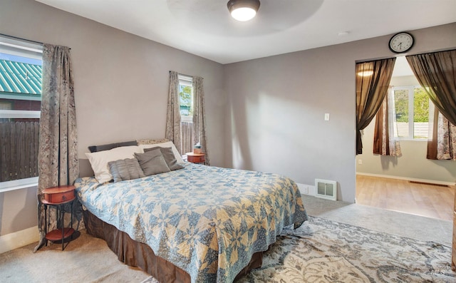 carpeted bedroom with multiple windows, baseboards, and a ceiling fan