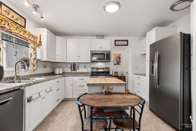 kitchen featuring white cabinets, appliances with stainless steel finishes, butcher block counters, light hardwood / wood-style floors, and sink