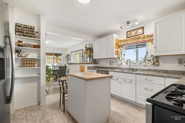 kitchen featuring butcher block counters, a kitchen bar, light wood-type flooring, white cabinets, and a center island