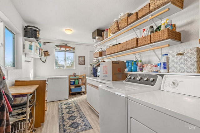 clothes washing area featuring washer and clothes dryer and light hardwood / wood-style flooring