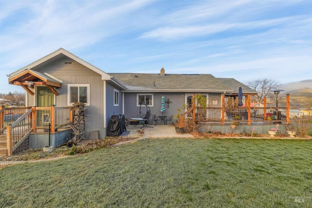 rear view of property with a deck, a yard, and a patio