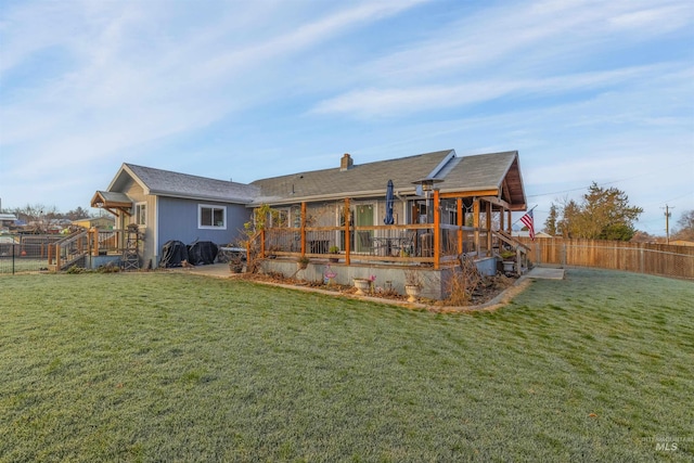 rear view of house featuring a lawn and a wooden deck