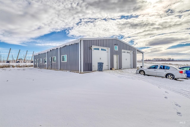 snow covered structure featuring a garage