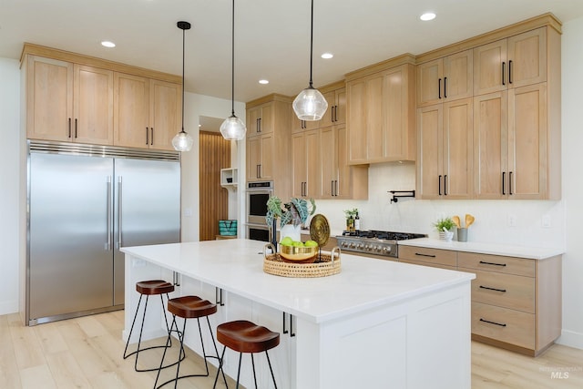 kitchen with light brown cabinets, hanging light fixtures, and appliances with stainless steel finishes