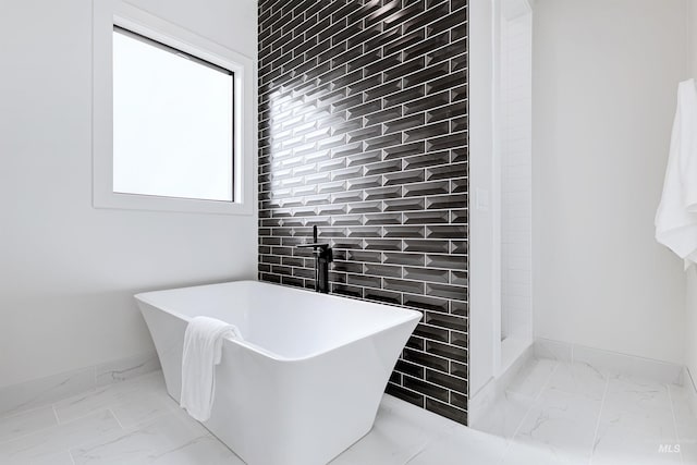 bathroom with a tub to relax in and tile walls