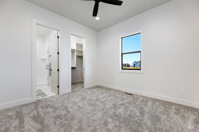 unfurnished bedroom featuring ceiling fan, a walk in closet, carpet floors, and a closet