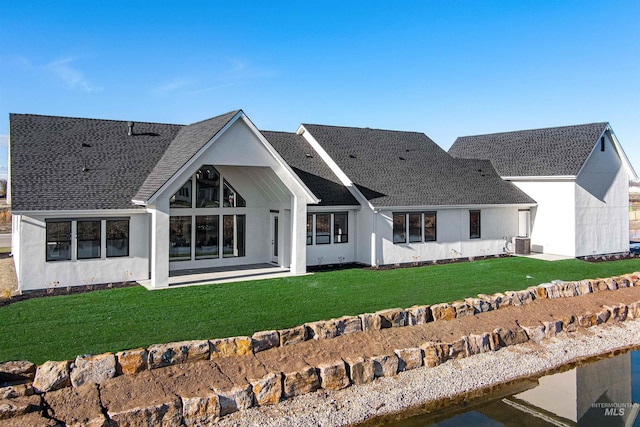 rear view of property featuring a lawn, central AC, and a patio