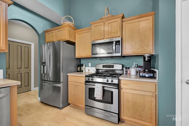 kitchen with light brown cabinetry, stainless steel appliances, and light hardwood / wood-style floors