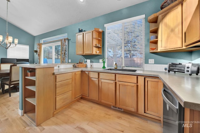 kitchen featuring sink, hanging light fixtures, vaulted ceiling, light hardwood / wood-style floors, and kitchen peninsula