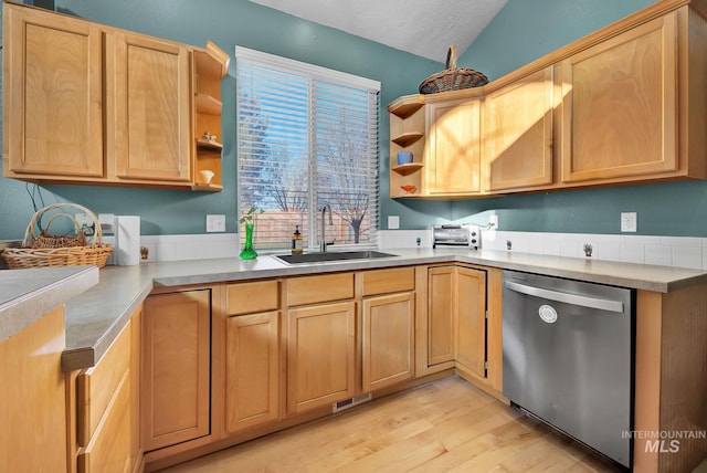 kitchen featuring stainless steel dishwasher, sink, light brown cabinets, light hardwood / wood-style flooring, and lofted ceiling