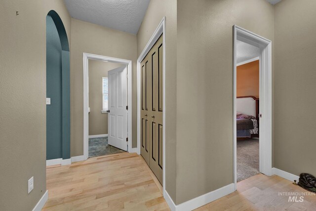 hallway featuring light hardwood / wood-style floors and a textured ceiling