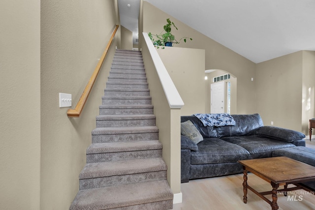 stairs featuring hardwood / wood-style floors and vaulted ceiling