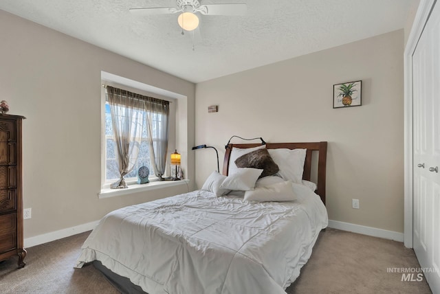 bedroom featuring a textured ceiling, ceiling fan, light carpet, and a closet