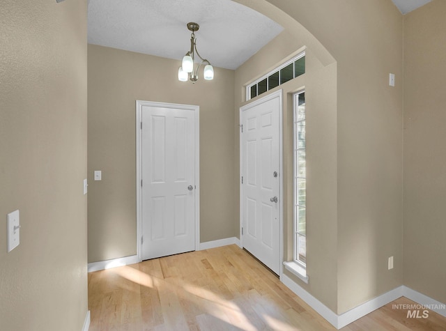 foyer featuring a textured ceiling, light hardwood / wood-style floors, an inviting chandelier, and a wealth of natural light