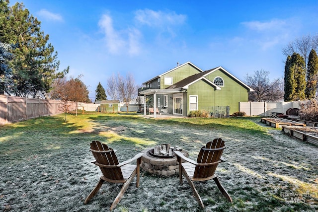 rear view of property featuring a patio area, a yard, and an outdoor fire pit