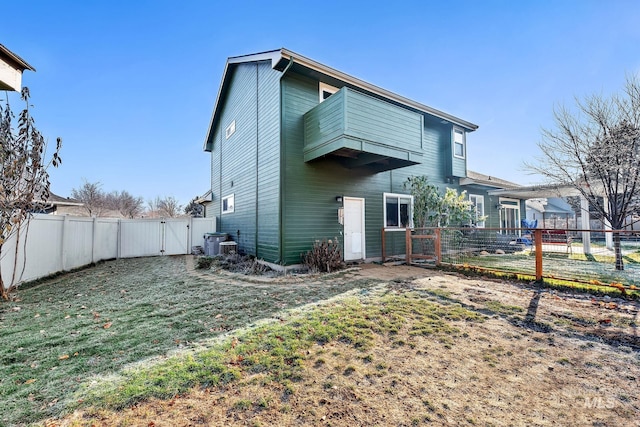 back of property featuring cooling unit and a lawn