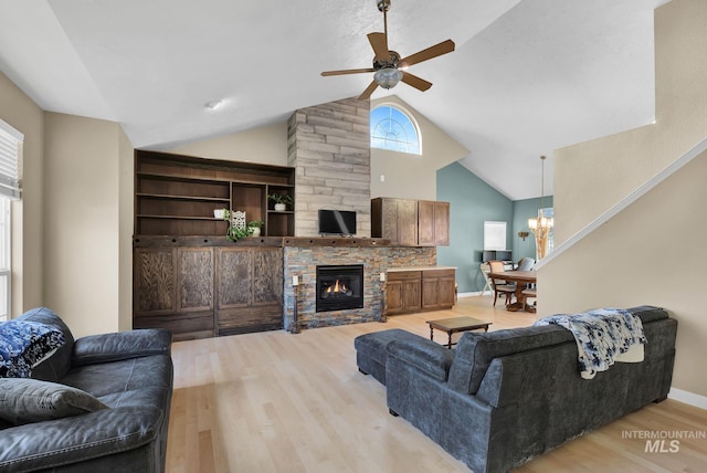 living room featuring a fireplace, ceiling fan with notable chandelier, high vaulted ceiling, and light hardwood / wood-style flooring