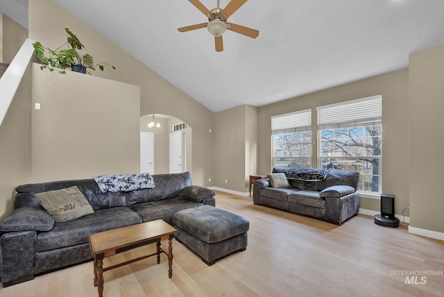 living room featuring ceiling fan with notable chandelier, light wood-type flooring, and high vaulted ceiling