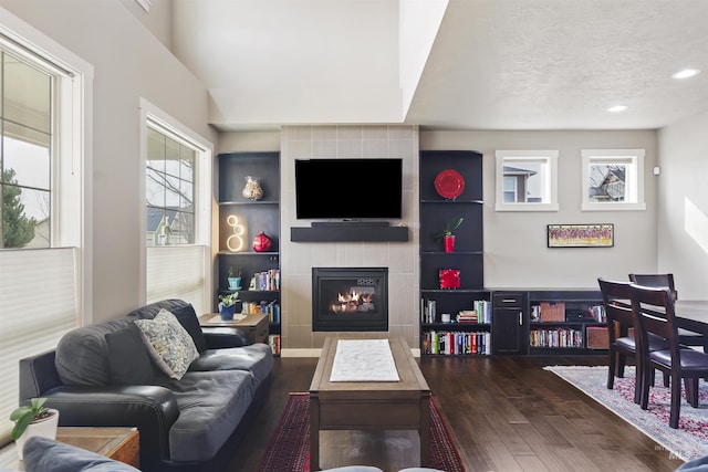 living area with dark wood-style floors, a fireplace, and a wealth of natural light