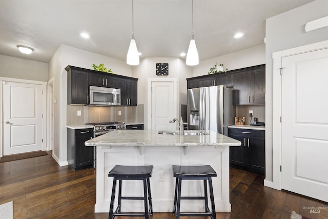 kitchen with appliances with stainless steel finishes, a breakfast bar area, a sink, and decorative backsplash