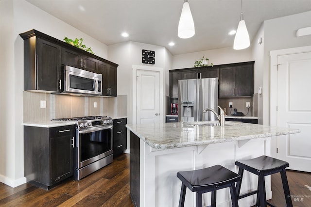 kitchen featuring tasteful backsplash, dark wood-style floors, appliances with stainless steel finishes, a breakfast bar, and a sink