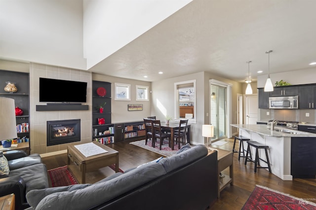 living area featuring dark wood-style floors, a fireplace, baseboards, and recessed lighting