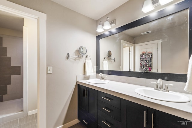 bathroom featuring double vanity, visible vents, baseboards, and a sink