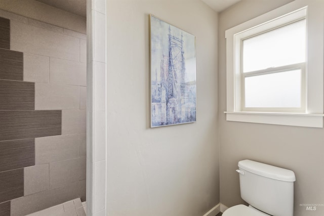 bathroom featuring toilet and a tile shower