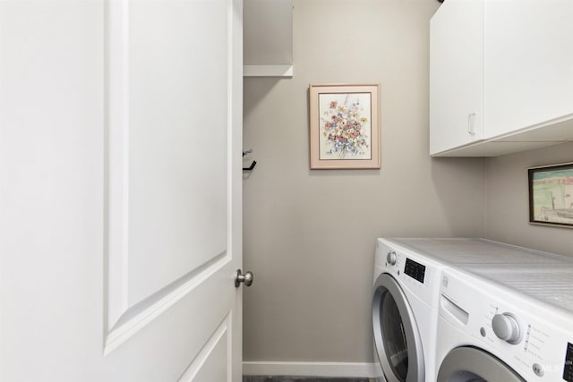 clothes washing area featuring washing machine and dryer, cabinet space, and baseboards