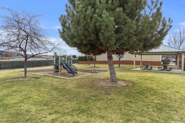 communal playground featuring a lawn, a patio area, and fence