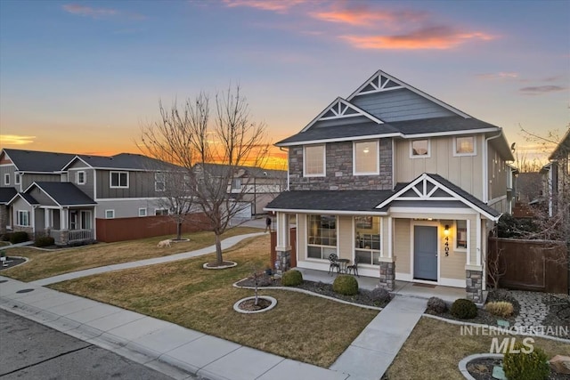 craftsman-style home with board and batten siding, a front yard, covered porch, and fence