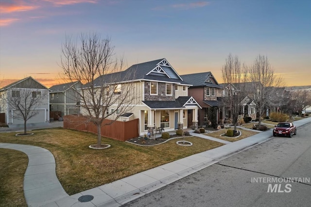 view of front facade with a residential view, fence, and a front lawn