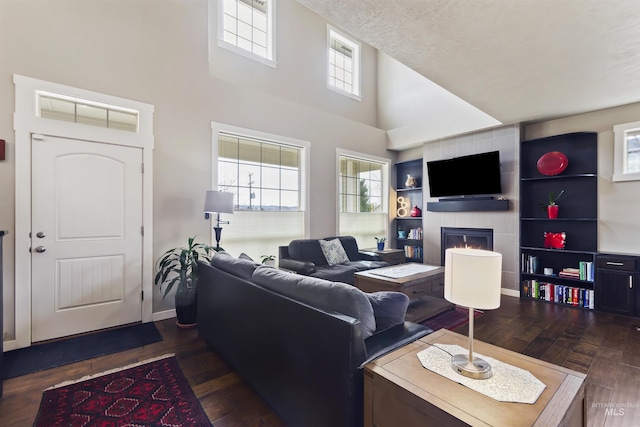 living room featuring dark wood-style floors, plenty of natural light, baseboards, and a tiled fireplace