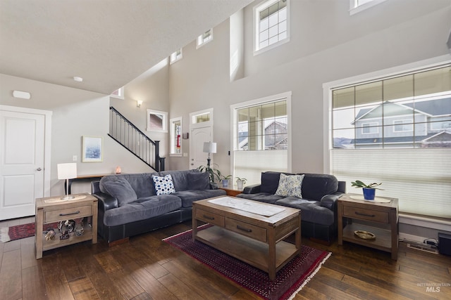 living room with wood-type flooring, visible vents, stairway, and a high ceiling