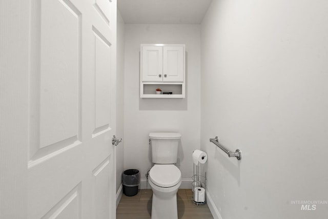 bathroom with wood finished floors, toilet, and baseboards