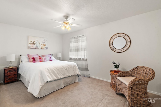 bedroom featuring light carpet, ceiling fan, baseboards, and a textured ceiling