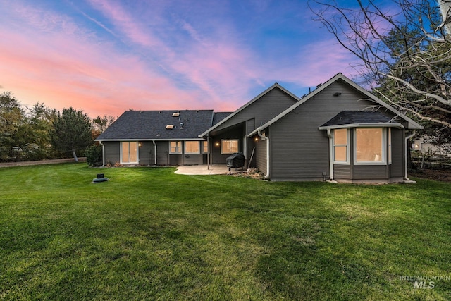 back of property at dusk featuring a patio area and a lawn