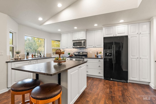 kitchen featuring dark countertops, dark wood-style floors, stainless steel appliances, and lofted ceiling