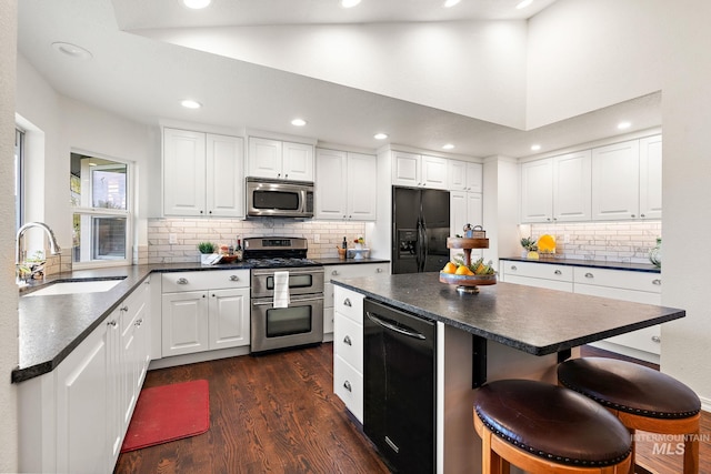 kitchen with stainless steel appliances, dark countertops, and a sink