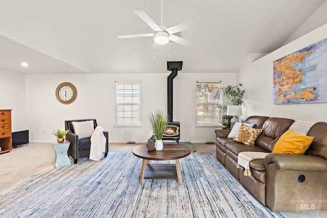 living area featuring a wood stove, carpet, baseboards, and vaulted ceiling