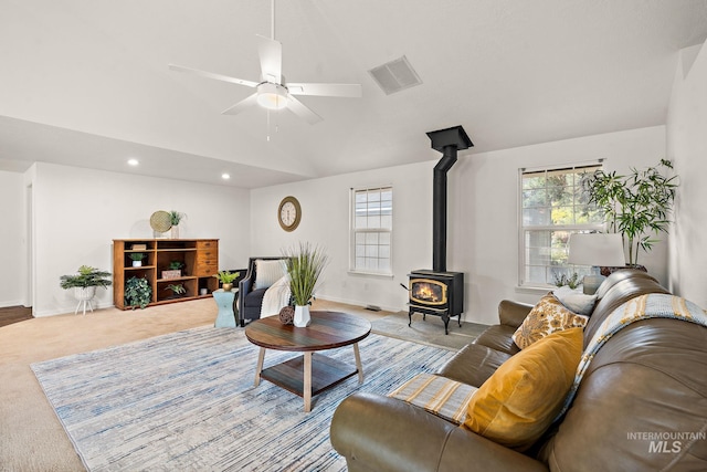 carpeted living area featuring lofted ceiling, recessed lighting, visible vents, baseboards, and a wood stove