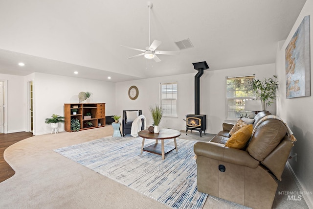 living area with lofted ceiling, recessed lighting, visible vents, a ceiling fan, and a wood stove