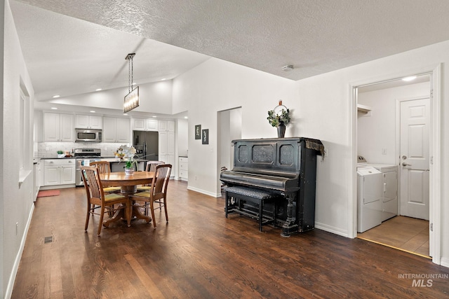 dining area featuring baseboards, lofted ceiling, dark wood-style flooring, a textured ceiling, and washing machine and dryer