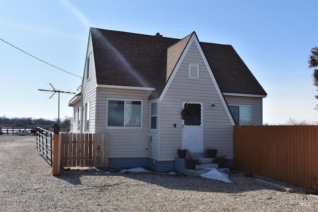 view of front of property featuring a shingled roof, entry steps, and fence